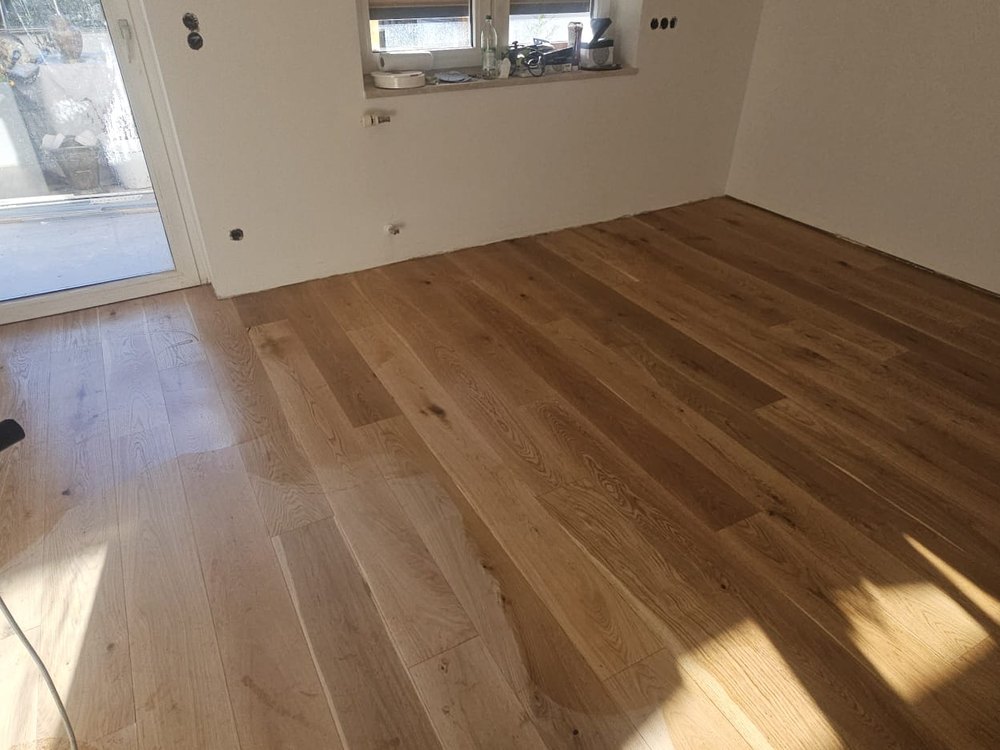Verlegung von Eichen-Parkett und Vinyl-Dielen in einem hellen modernen Raum im Raum München